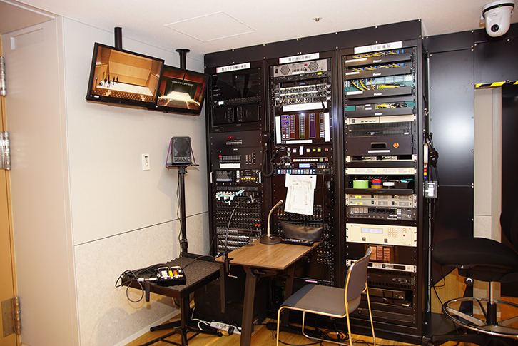 音楽ホールの舞台袖。音響設備架と影アナスペース。