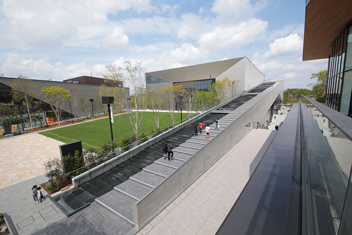 緩やかなステップを流れ落ちる水の滑走路。そこから大空へ飛行機が飛び立つさまをイメージできる、美しい中庭から臨むホール外観